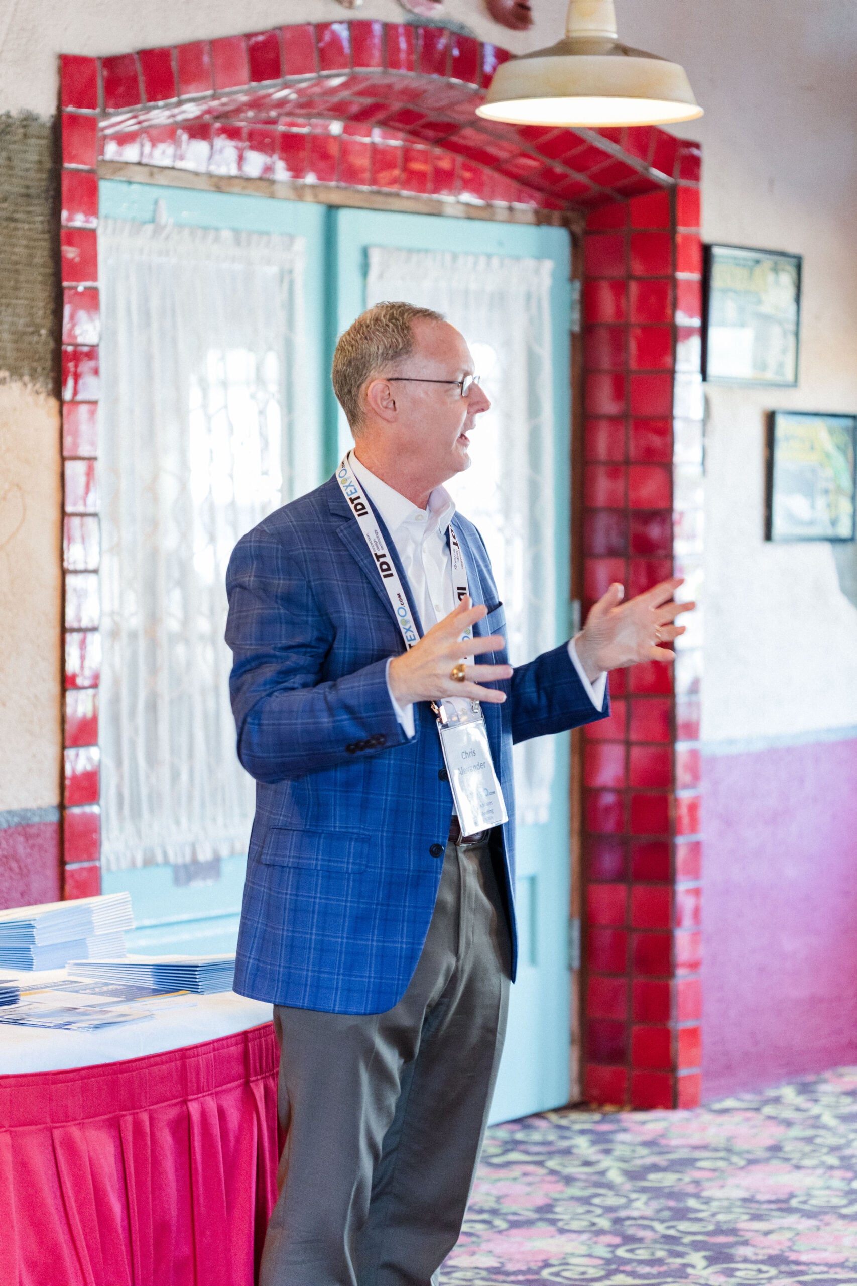 Dr. Chris Alexander stands with his hands out as he lectures in a banquet hall.